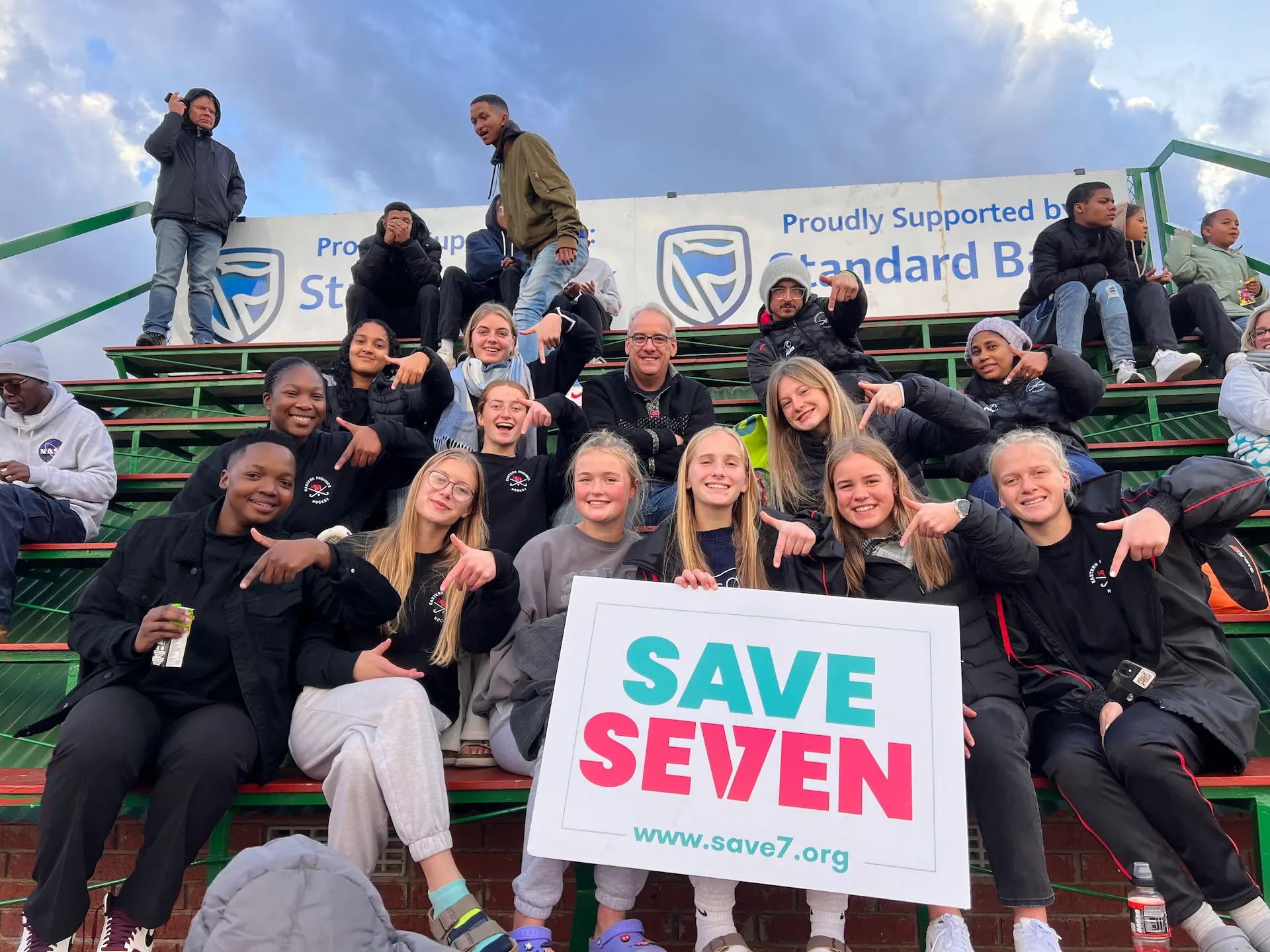 SaveSeven team members holding a sign saying 'Save7'